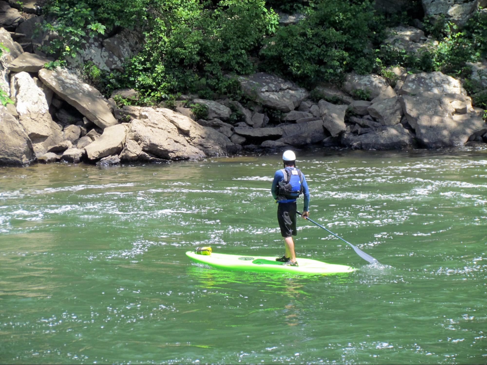 A tourist on a paddle board in Ohiopyle State Park, Pennsylvania, USA.
