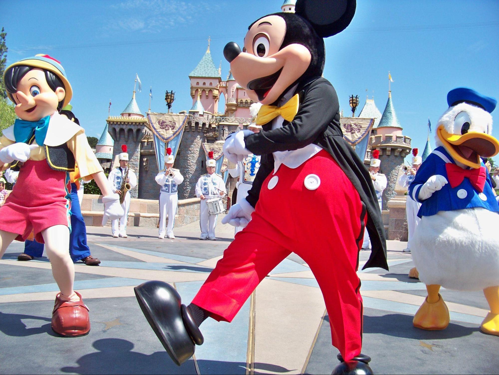 Disney character, Mickey Mouse, Pinnochio, and Donald Duck march in front of the Disney castle.