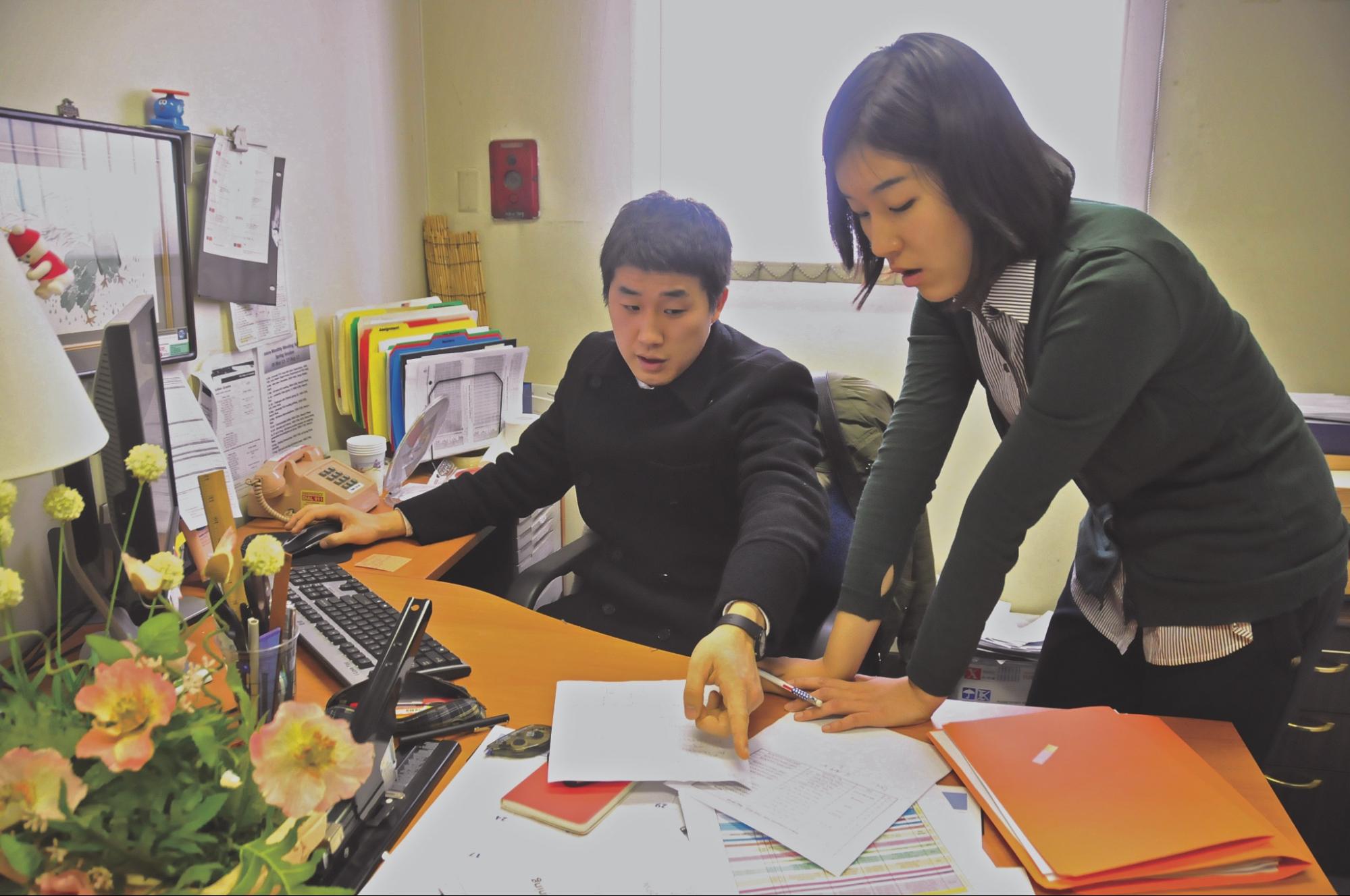 A supervisor shows an intern a document.