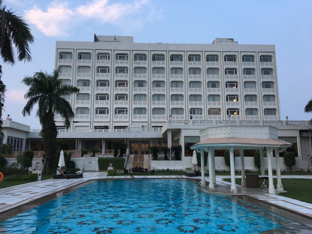 A small, white hotel, with a pool and gazebo in front of the building.