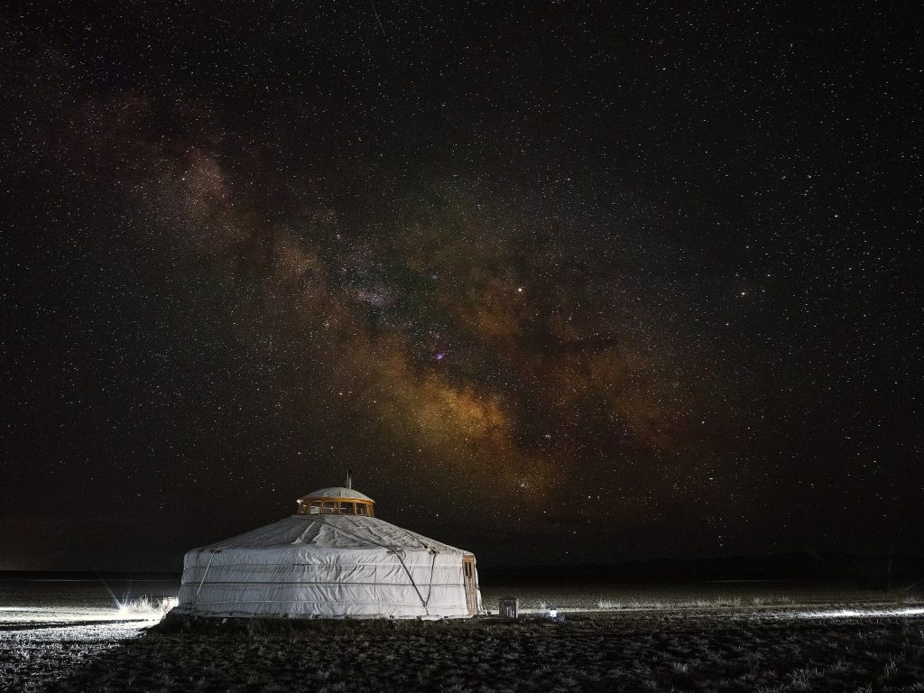 A white, domed tent sides under a night sky filled with stars.
