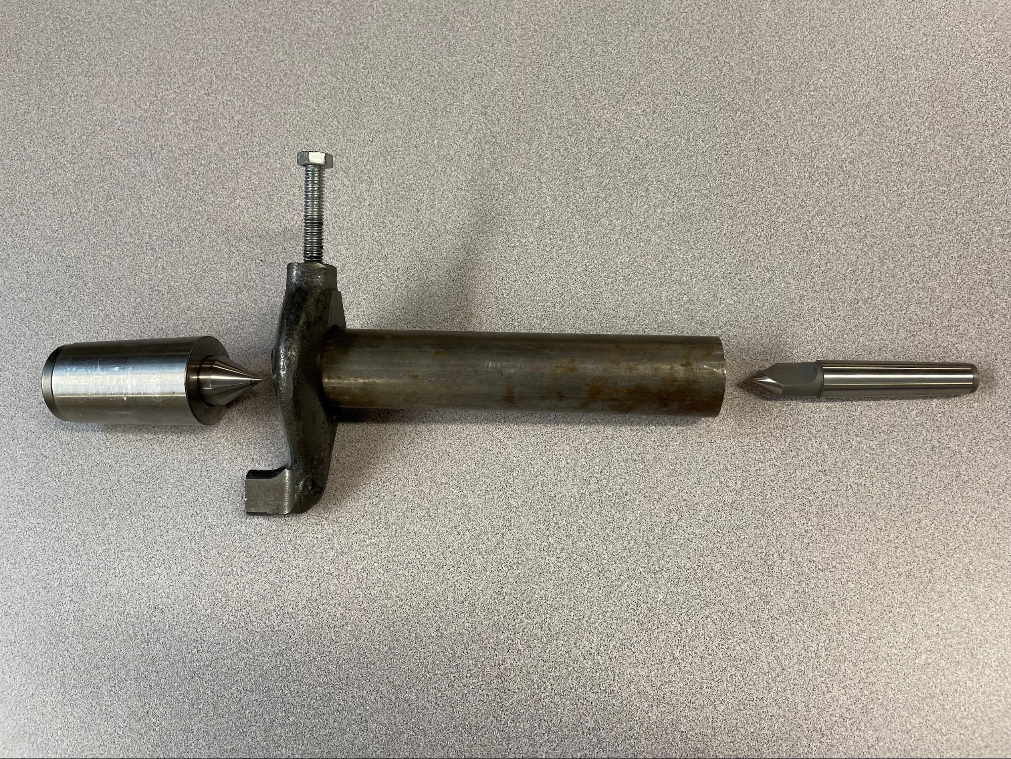 A spindle center on the left and a dead center on the right, simulating turning a part between centers with a lathe dog attached.