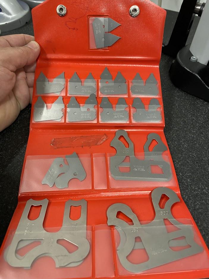 A set of metal radius gages in a red plastic sleeve.