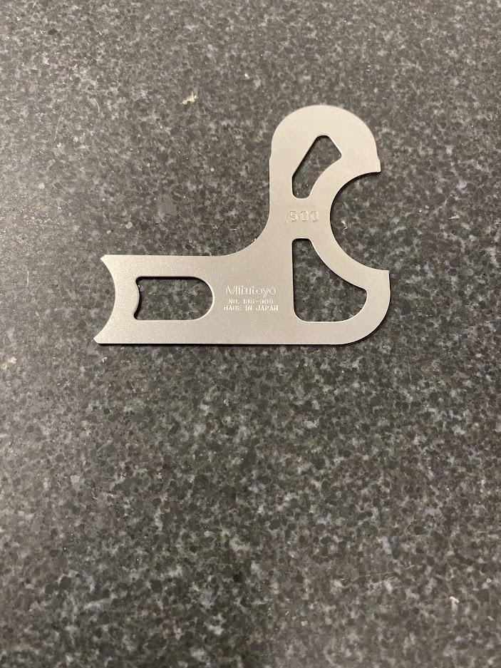 A metal radius gage with five different radius shaped sides.