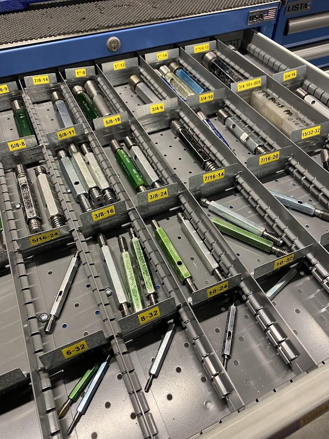 A drawer with an assortment of thread gages.