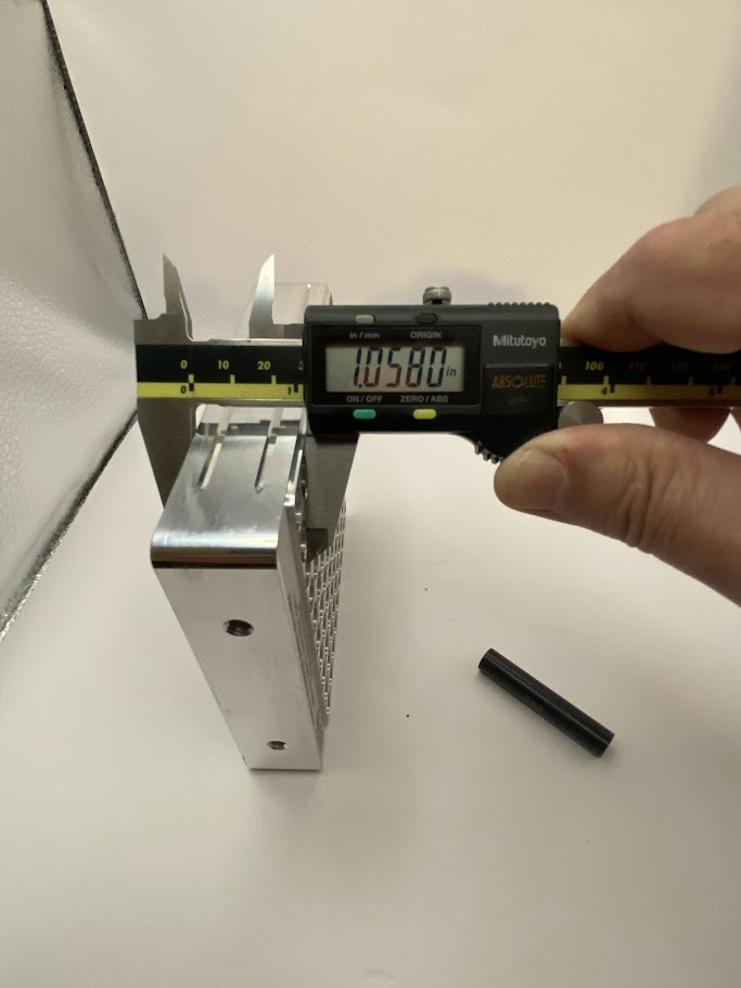 A digital caliper is placed over the larger thickness of a part.