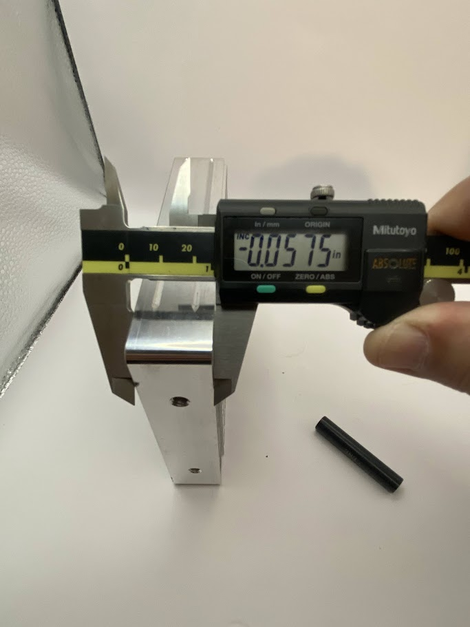 The caliper is closed on the shorter height of the part, and the display indicates .057”.