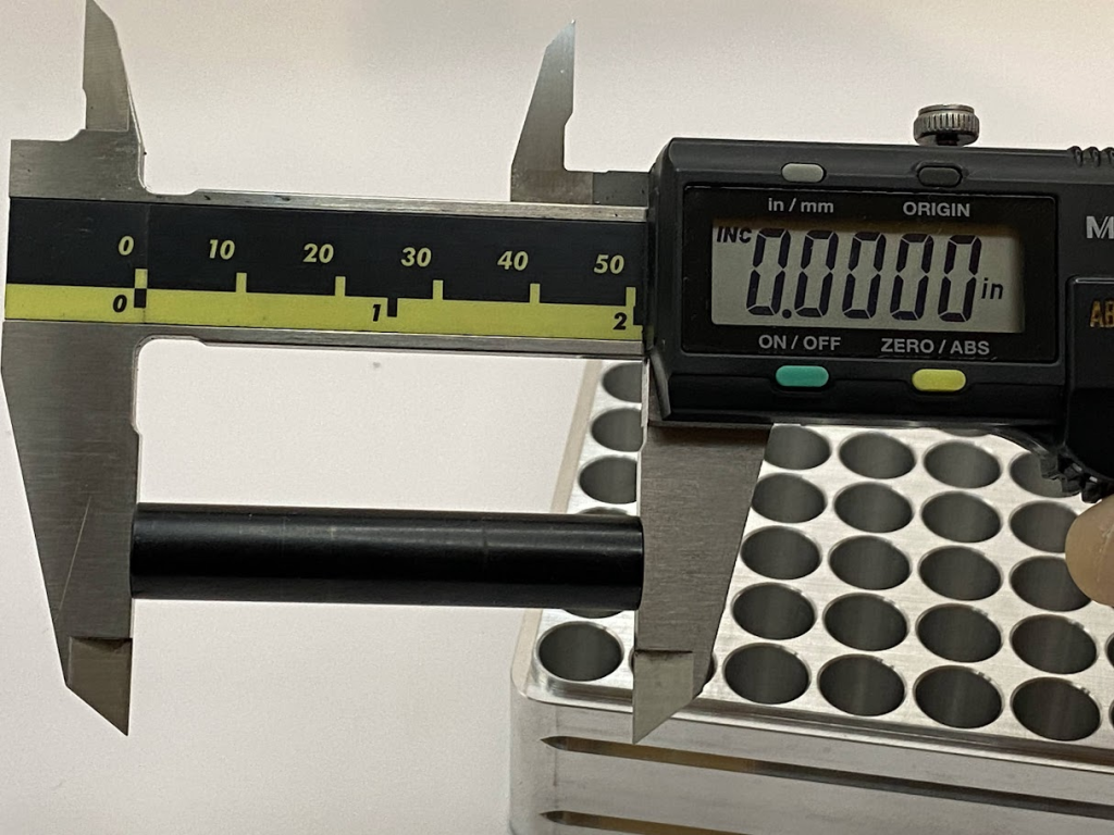 A digital caliper is held against the length of an inspection pin while the incremental button is pressed, establishing a temporary zero.