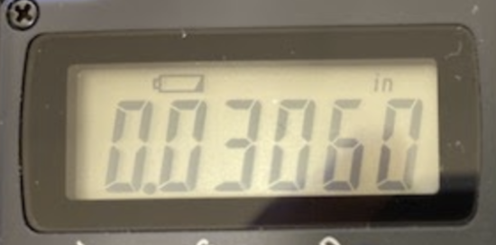 The digital display of a measuring device has a low battery symbol illuminated.