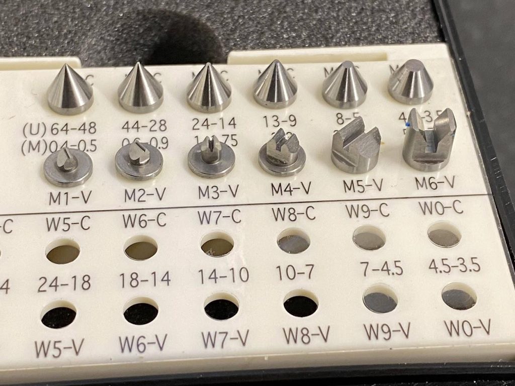 A plastic case with holes and labeling to identify the different anvils for the thread micrometer.
