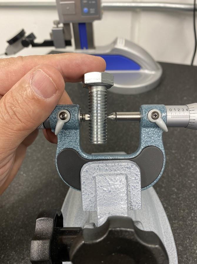 A thread mic is closed over the threads of a bolt.