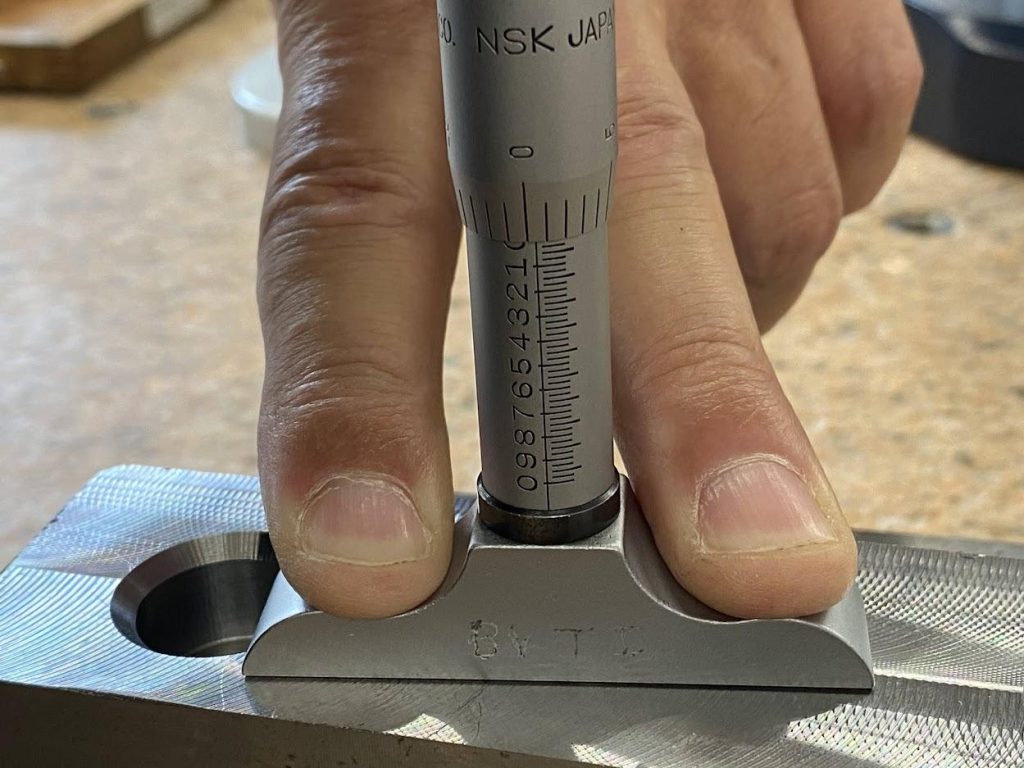 An operator is holding the depth mic tight against the surface of a part.