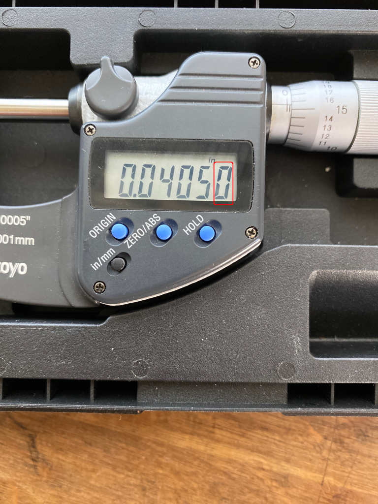 A digital micrometer with a five decimal digit display, showing the number 0.04050.