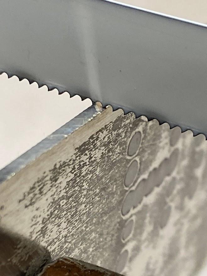 An enlarged image showing two teeth in contact with the metal being cut.