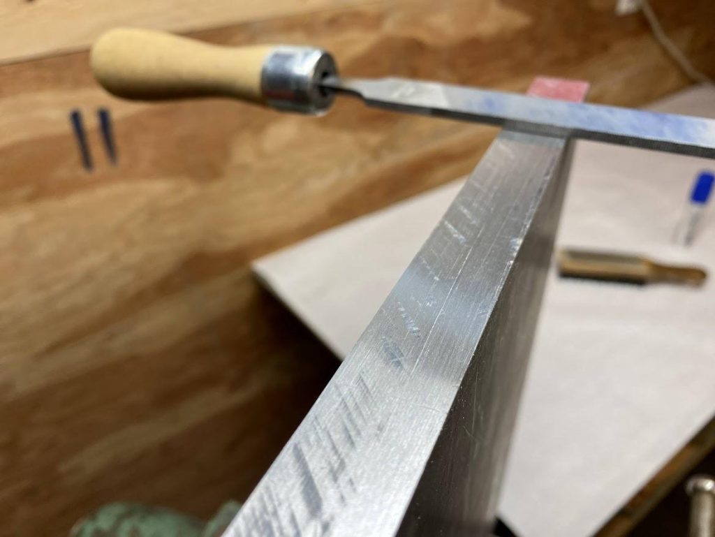 A file resting on a freshly filed edge of an aluminum plate.