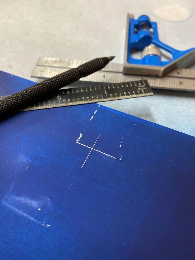 A plate of aluminum with layout fluid applied to its surface with cross marks scratched into the surface.