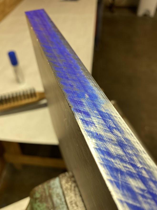 The dyed edge of aluminum stock has shiny spots where a file removed material.