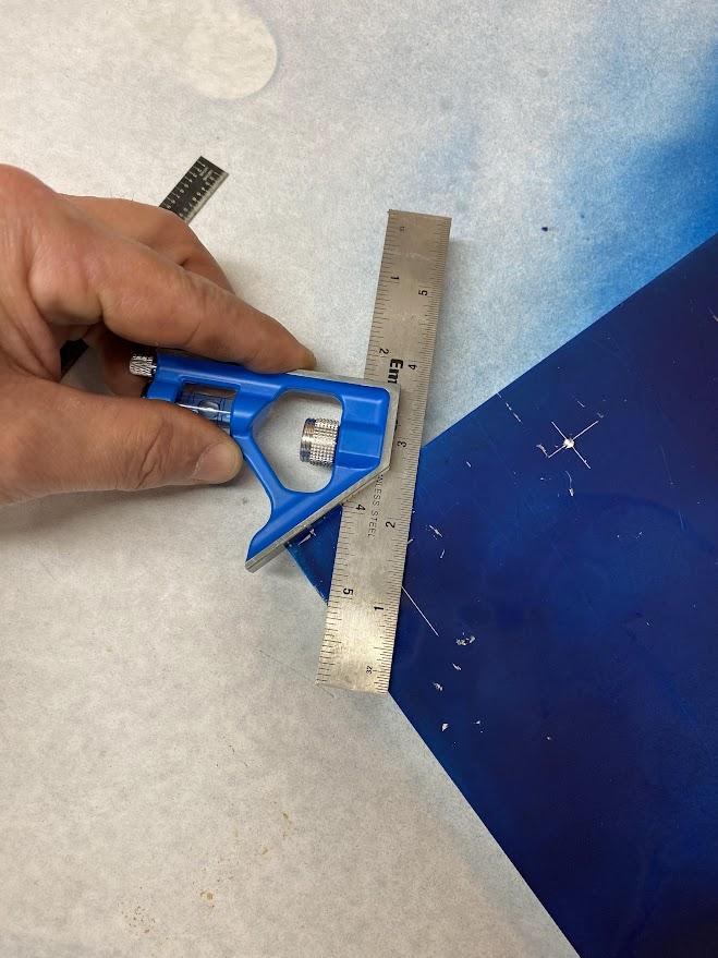 A combination square placed against the edge of the stock using the 45 degree edge.