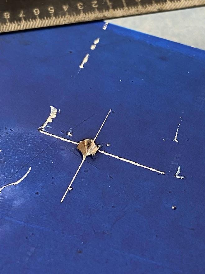 A close up view of material displaced from the point of a punch when struck with a hammer.