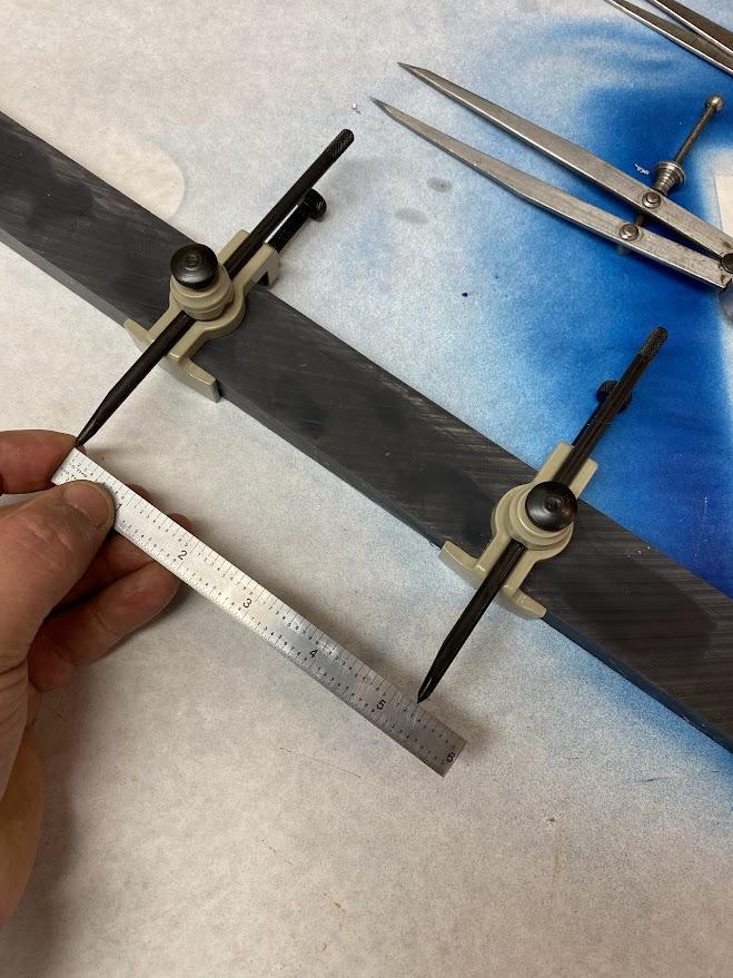 Two trammel points clamped to a straight piece of stock.