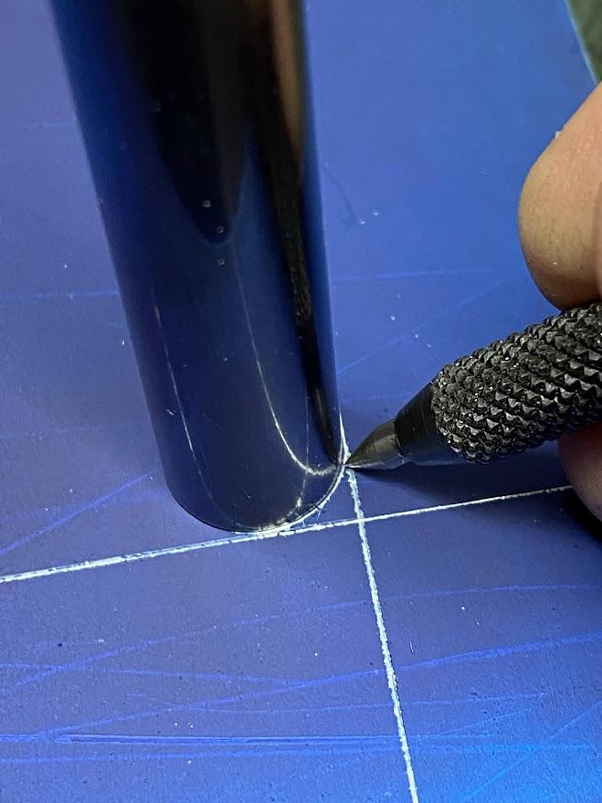 A scribe creating a layout arc using the surface of a gage pin as a guide.