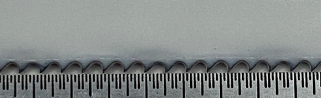 An enlarged view of the shape of the teeth on a hacksaw blade.