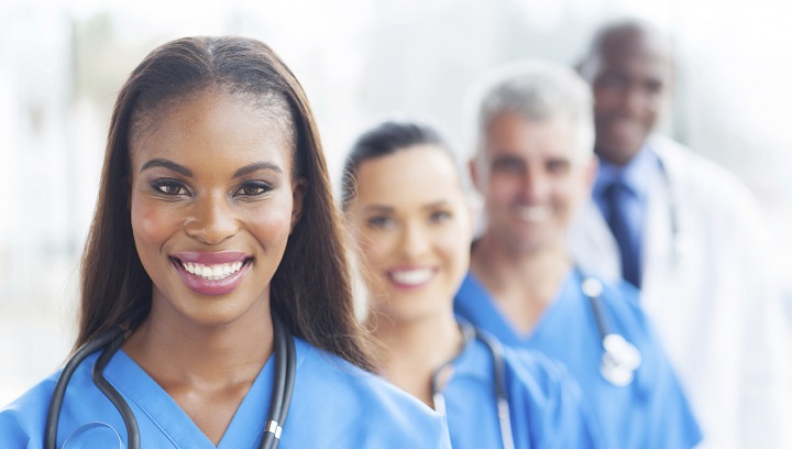 four smiling healthcare professional in scrubs with stethoscopes around their necks