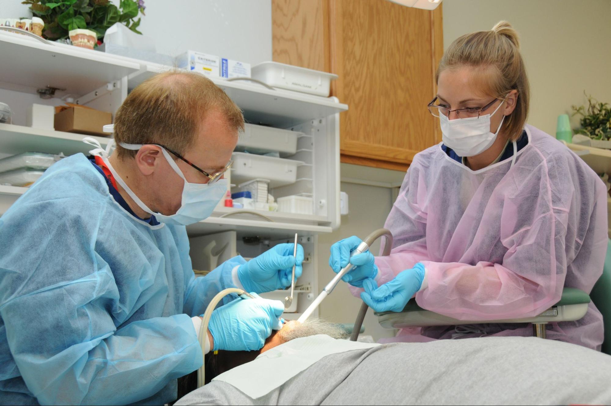 Two dental professionals working on a patient’s mouth