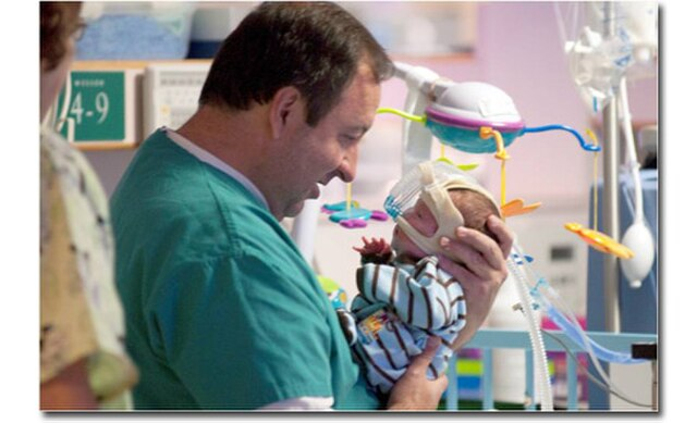 Healthcare professional holding an infant in the NICU