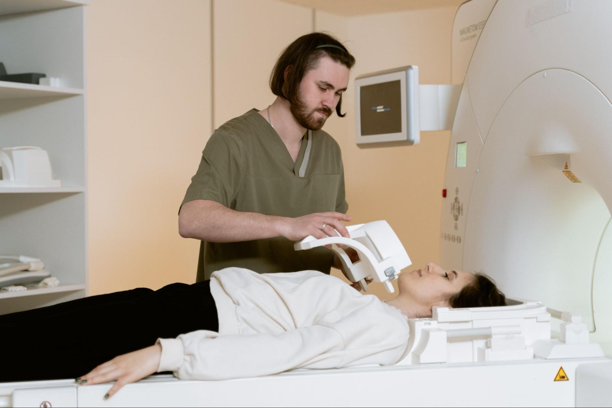 A CT technician applying supportive equipment to a patient’s neck before they enter the CT scanner.