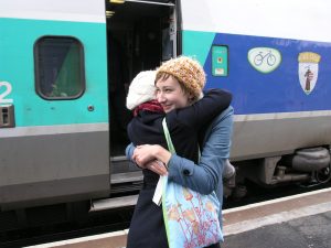 Two women hugging at a train station.