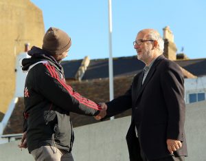 Two people exchange a warm handshake in public