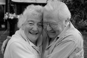 an older couple hugs while smiling at eachother