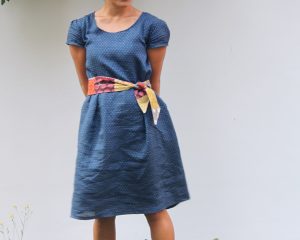 A person wearing a dress with a bow tied around the waist.