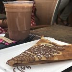 a chocolate crepe with chocolate beverages in the background