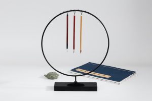Japanese writing set containing a black metal hoop with three dangling stylus.