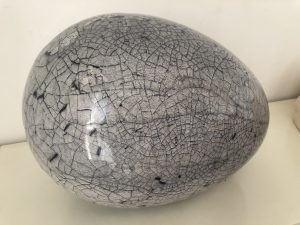 A smooth ovular stone, in gray with many small black cracks running along its surface.