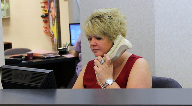 A woman receptionist answering a phone at Suburban Eye Care
