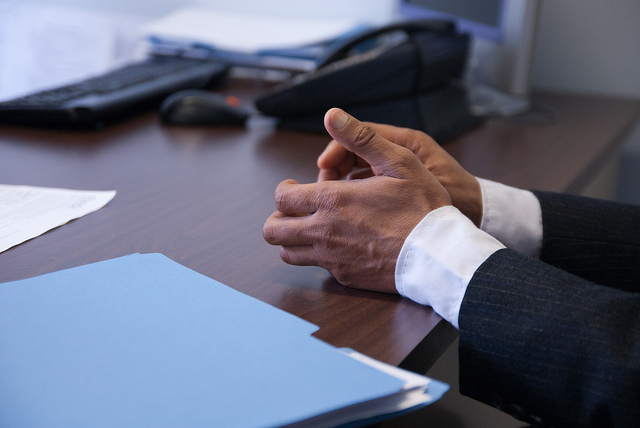 A man's hands on a desk during an interview