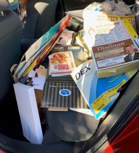 A pile of paper for recycling in the backseat of a car.