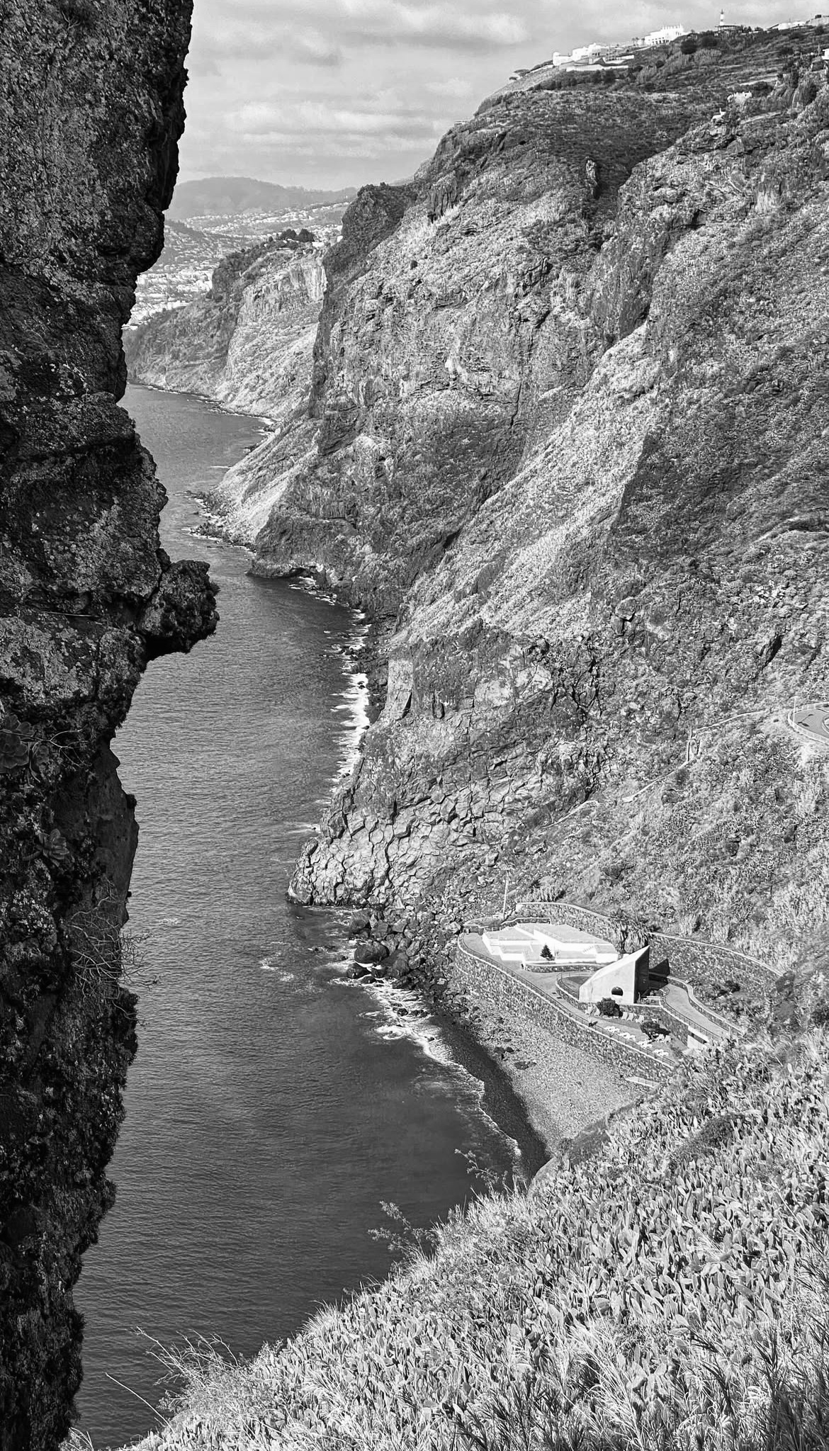 Black and white photograph of river valley between craggy mountains on both sides