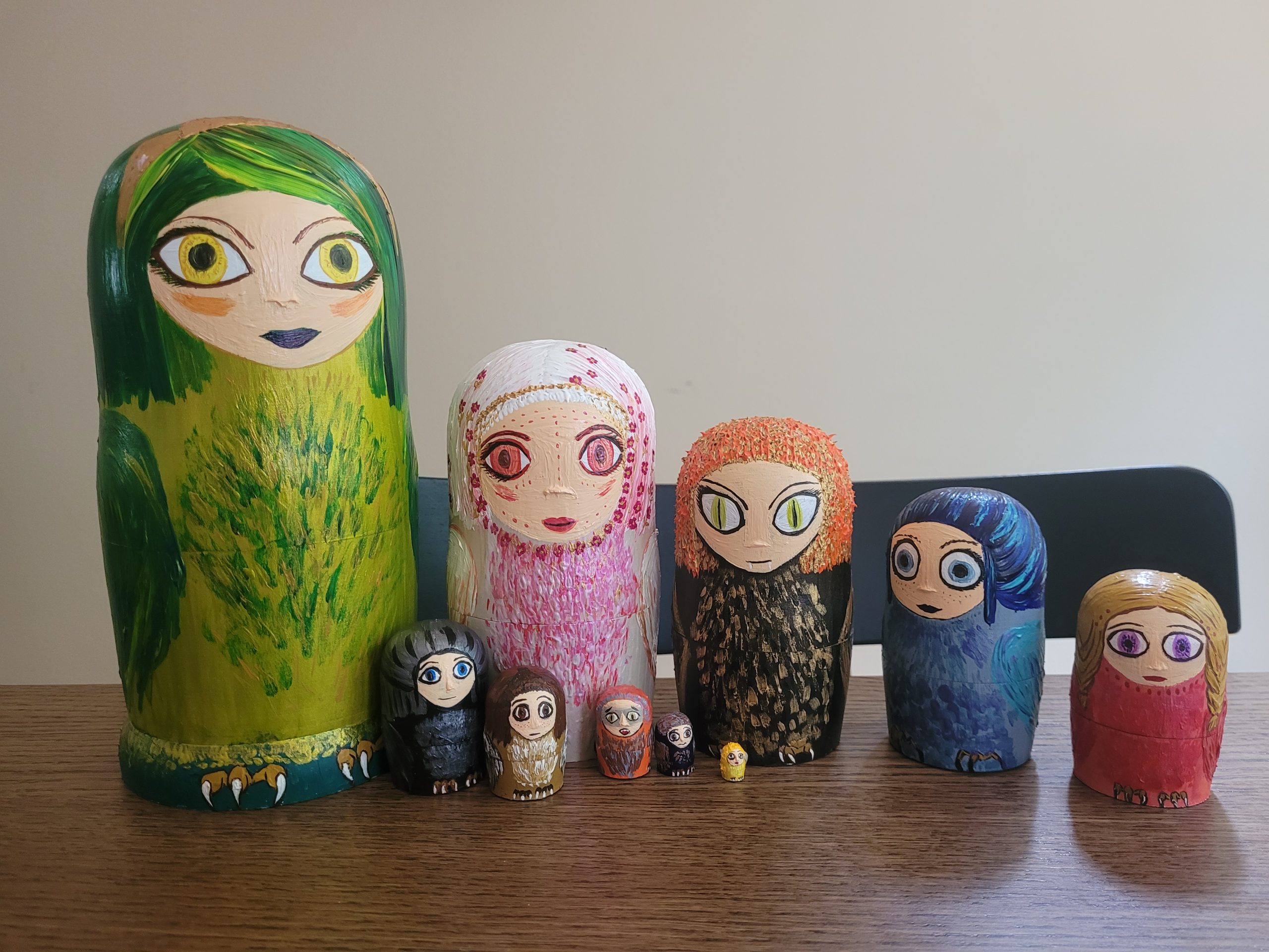 Ten nesting dolls which are decorated to look like birds with human faces