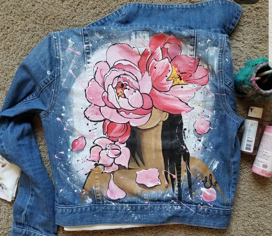 Painting of flowers over a face on the back of a jean jacket