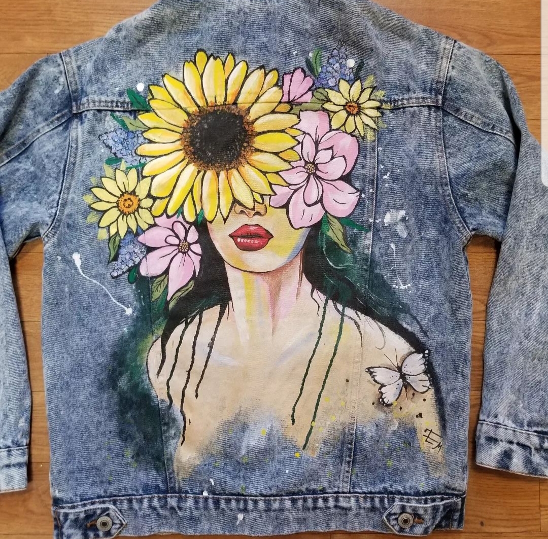 Painting of sunflowers over a face on the back of a jean jacket