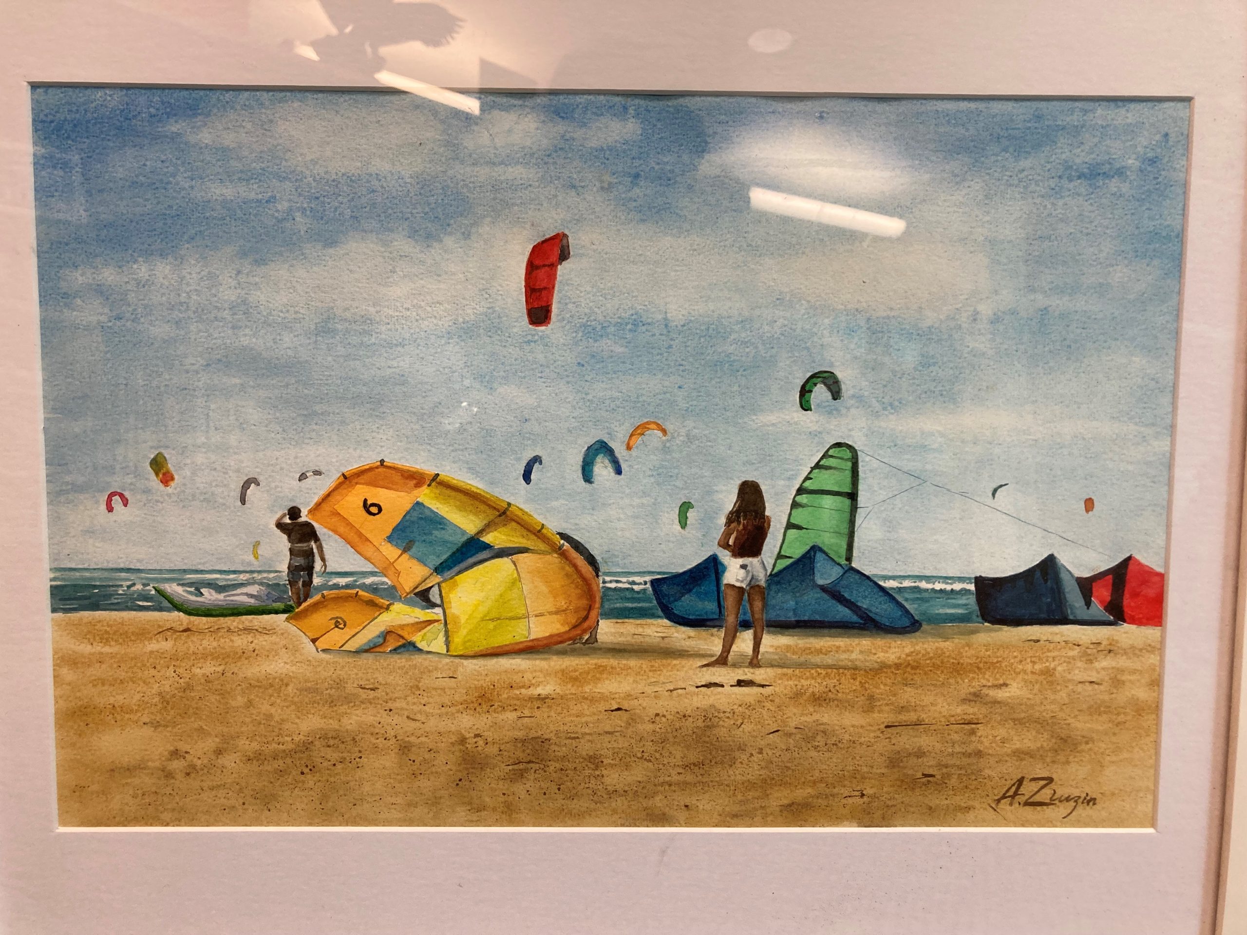 Watercolor painting of a beach with kites and wind surfers and two people looking at the water