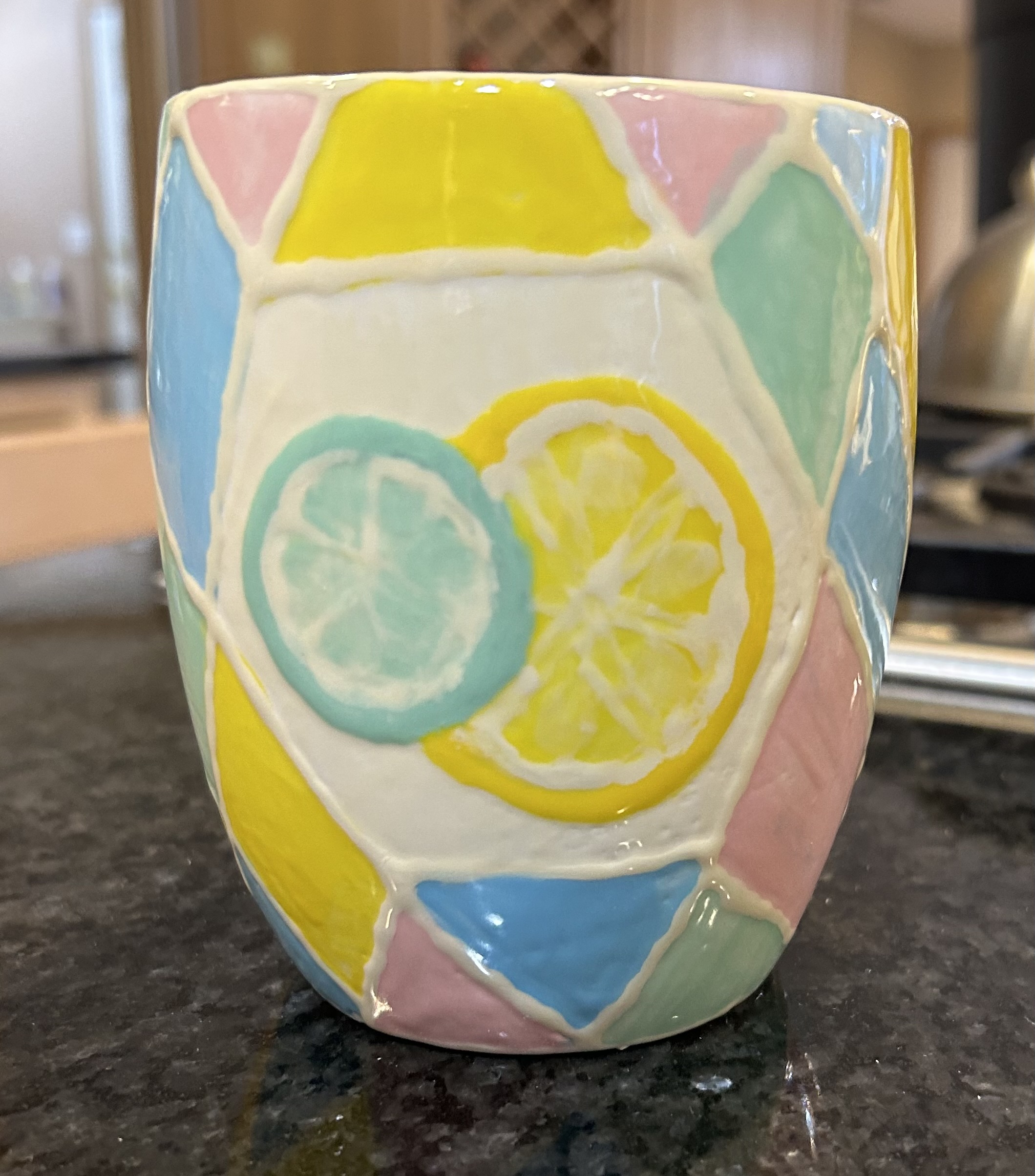 Ceramic mug with geometric pastel shapes and a lemon and lime wedge - front of mug