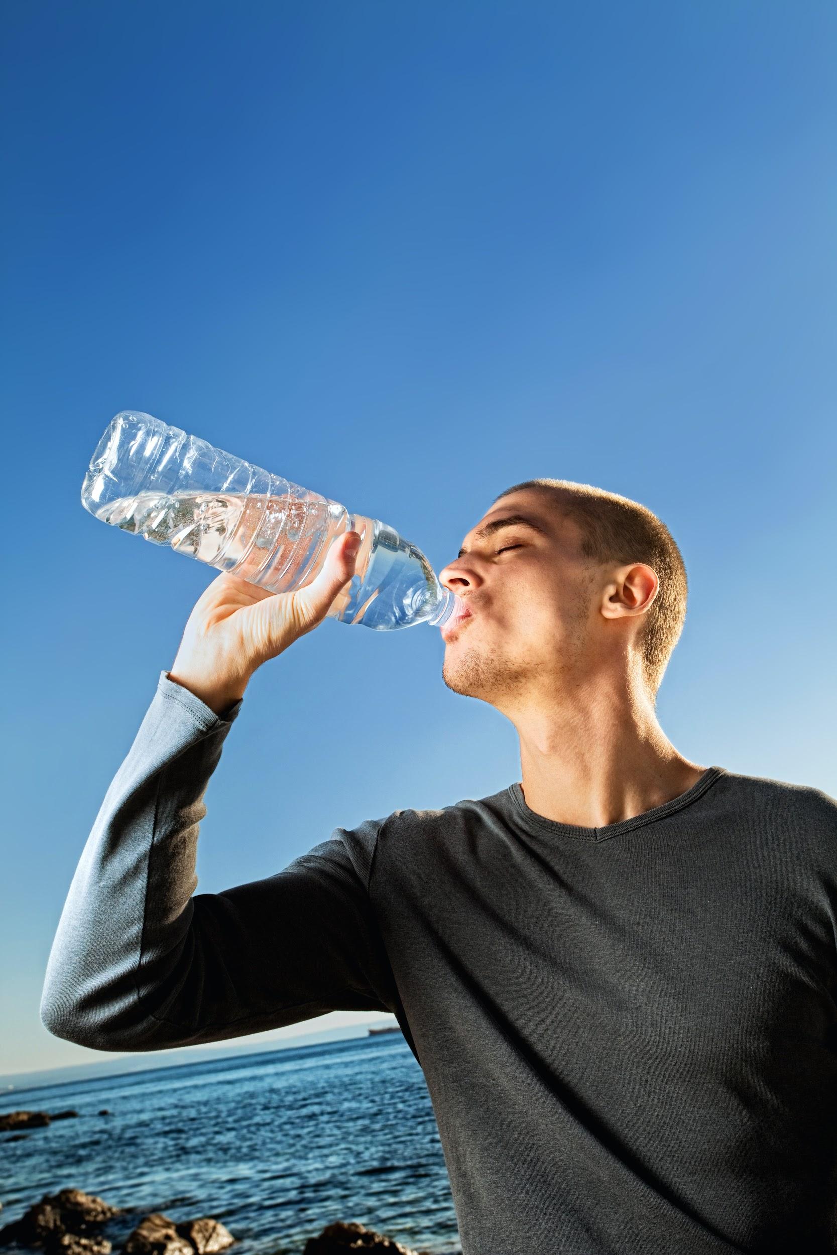 A man dressed in workout clothes drinks from a bottle of water.