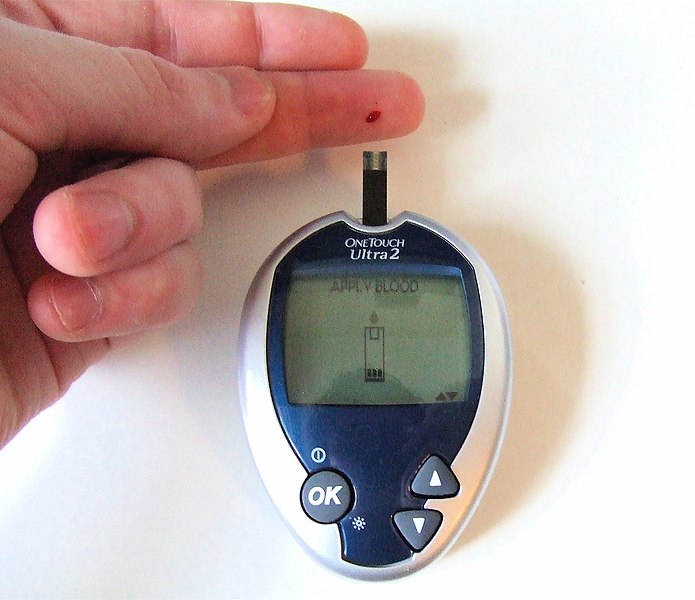 Photo showing capillary blood glucose testing in progress on a finger tip