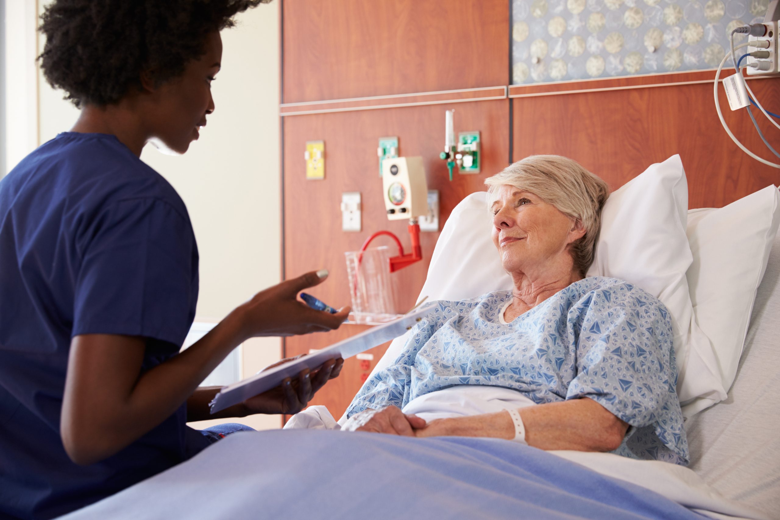 Image showing a nurse speaking with an elderly patient who is sitting up in a hospital bed