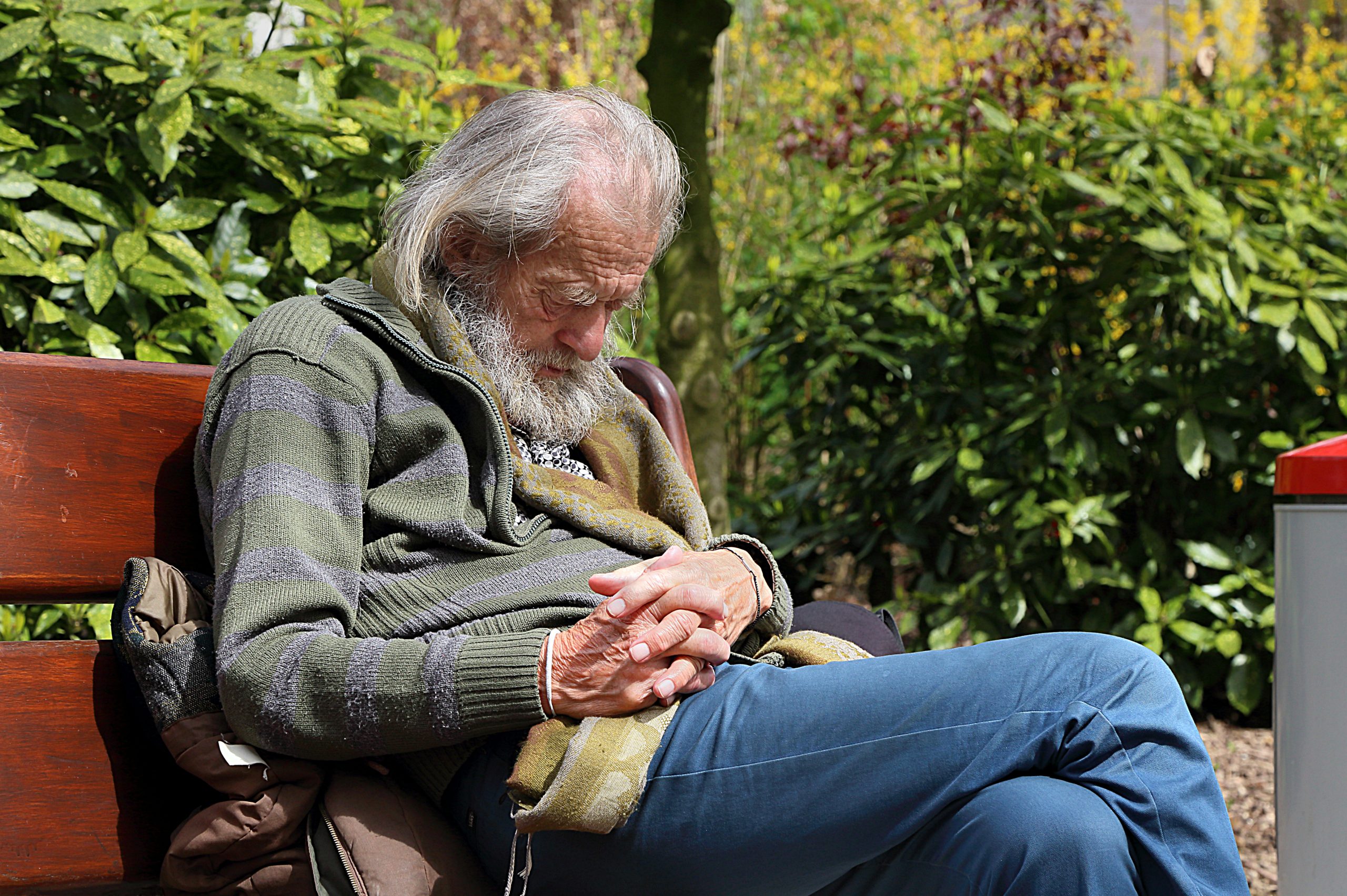 Image of elderly man sleeping on a park bench